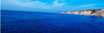 image of bright blue ocean with land in the distance on the right